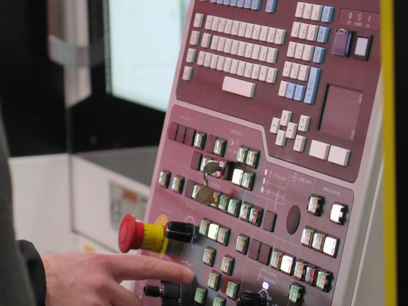 Bedieningspaneel van een CNC-machine bij Combifit Metaalbewerking, waarbij een operator instellingen invoert voor nauwkeurige metaalbewerking.