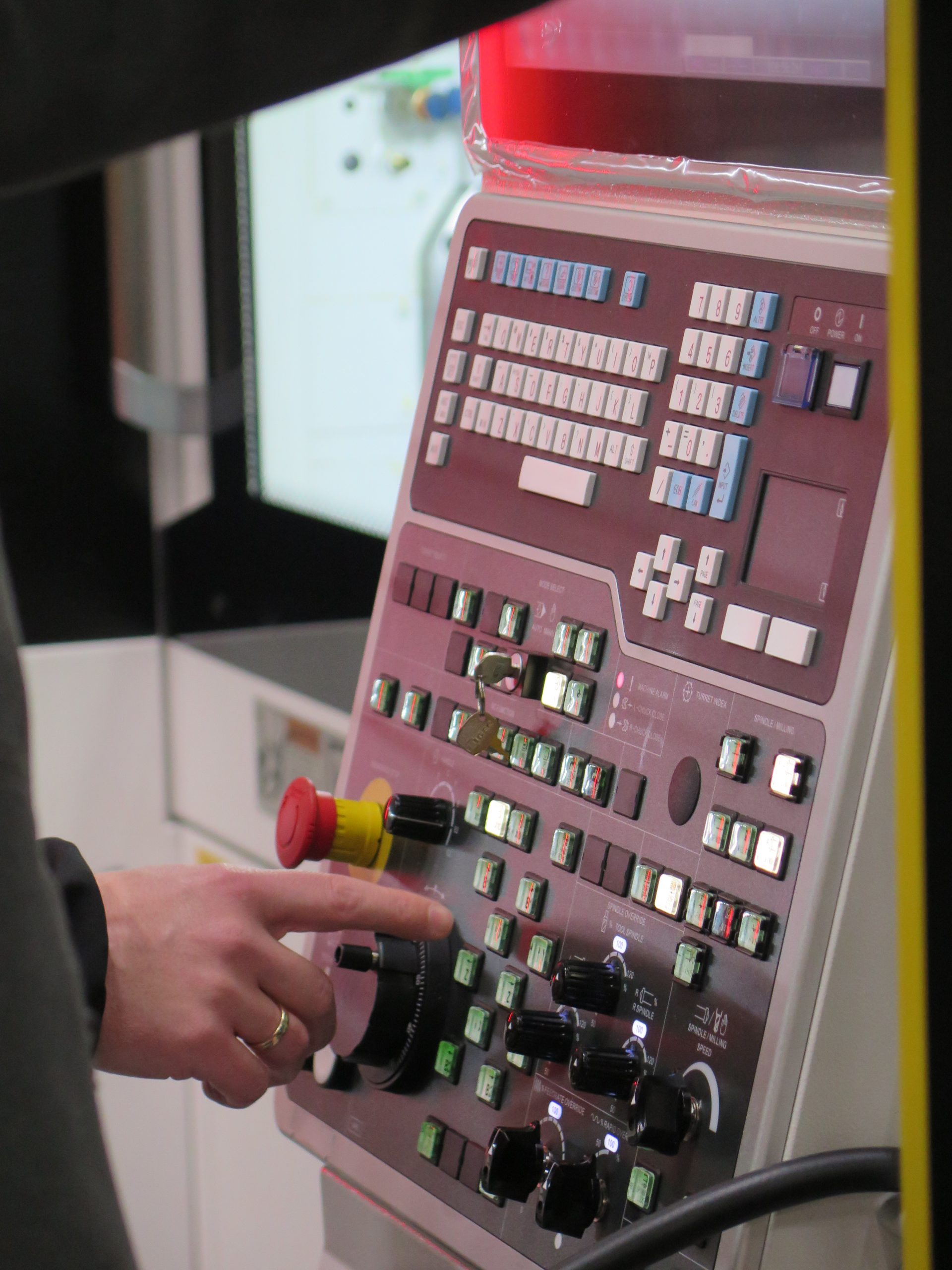 Bedieningspaneel van een CNC-machine bij Combifit Metaalbewerking, waarbij een operator instellingen invoert voor nauwkeurige metaalbewerking.